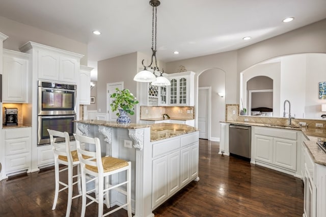 kitchen with appliances with stainless steel finishes, a sink, a kitchen island, backsplash, and recessed lighting