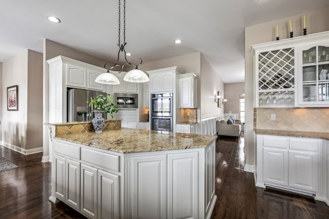 kitchen with appliances with stainless steel finishes, white cabinets, a kitchen island, decorative backsplash, and recessed lighting