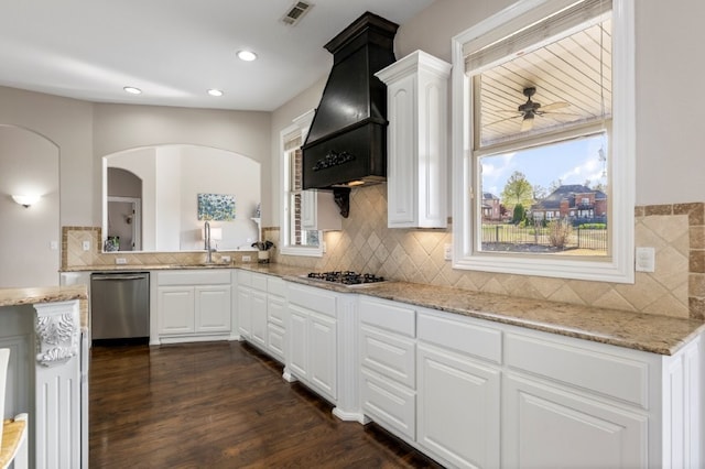 kitchen featuring appliances with stainless steel finishes, custom range hood, a sink, white cabinetry, and light stone counters