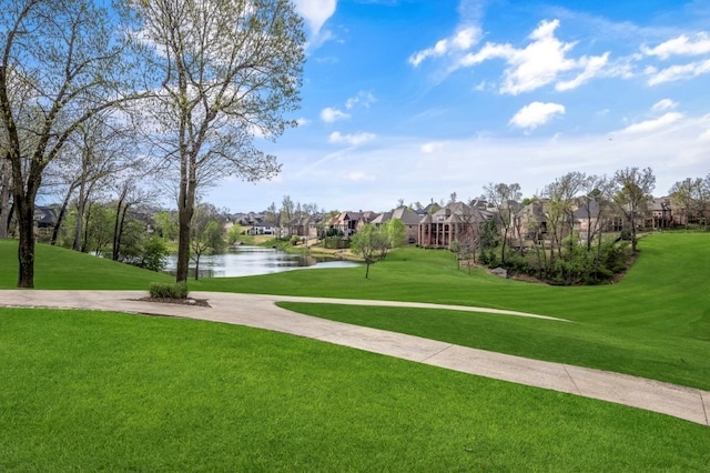 view of community with a residential view, a water view, a lawn, and golf course view