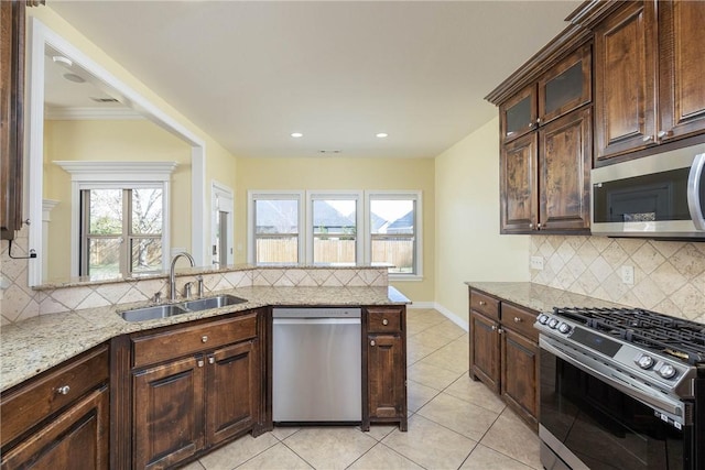 kitchen featuring tasteful backsplash, light stone countertops, a sink, and appliances with stainless steel finishes