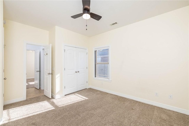 unfurnished bedroom with visible vents, baseboards, a closet, and light carpet