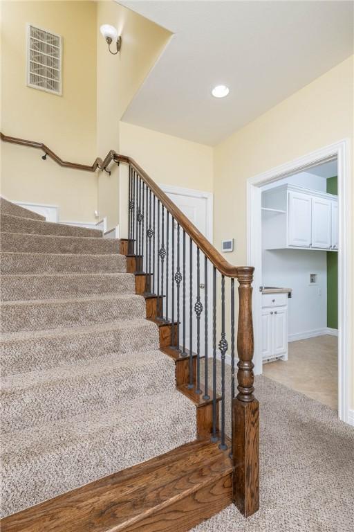 staircase with baseboards, visible vents, and carpet floors
