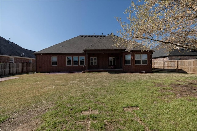 back of property featuring brick siding, a fenced backyard, a lawn, and a patio area