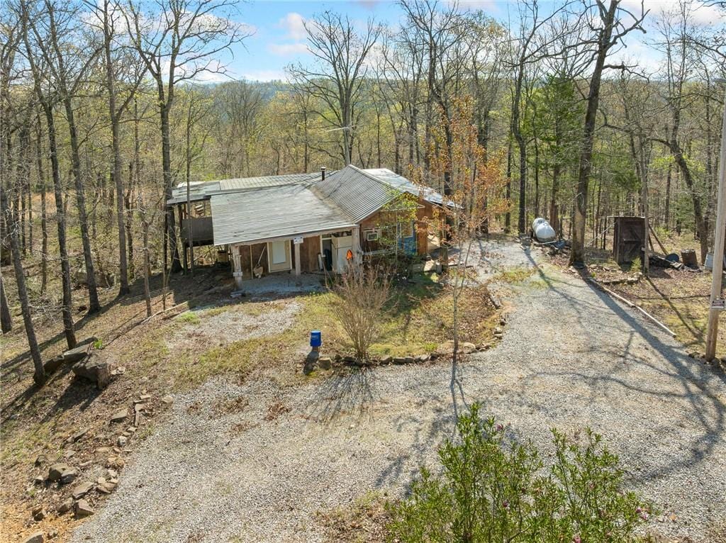 view of front of property featuring metal roof, a forest view, and dirt driveway