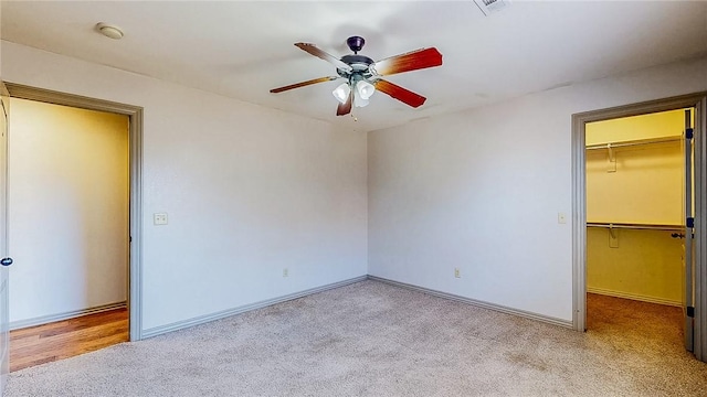 unfurnished bedroom featuring a closet, baseboards, a spacious closet, and carpet floors