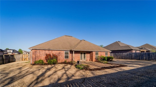 rear view of house with a fenced backyard, brick siding, and a patio