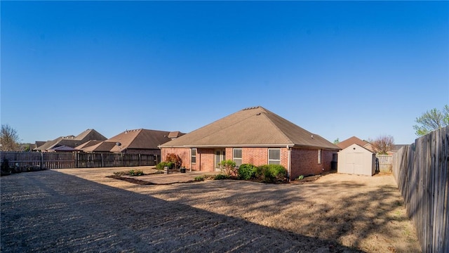 back of house with a storage shed, a fenced backyard, an outdoor structure, and brick siding