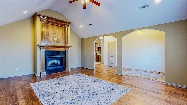 unfurnished living room with arched walkways, vaulted ceiling, a ceiling fan, and visible vents
