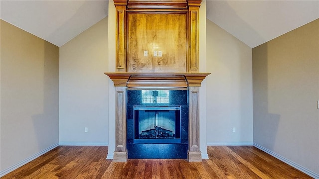 room details featuring wood finished floors, baseboards, and a glass covered fireplace