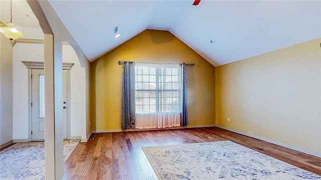 interior space with arched walkways, visible vents, wood finished floors, lofted ceiling, and baseboards