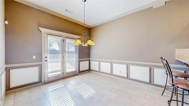 unfurnished dining area featuring a wainscoted wall, visible vents, a chandelier, crown molding, and light tile patterned floors