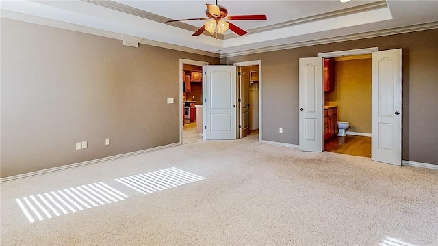 unfurnished bedroom with a spacious closet, carpet, baseboards, and a raised ceiling