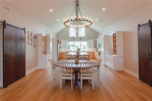 dining room featuring light wood-style floors, an inviting chandelier, and a barn door
