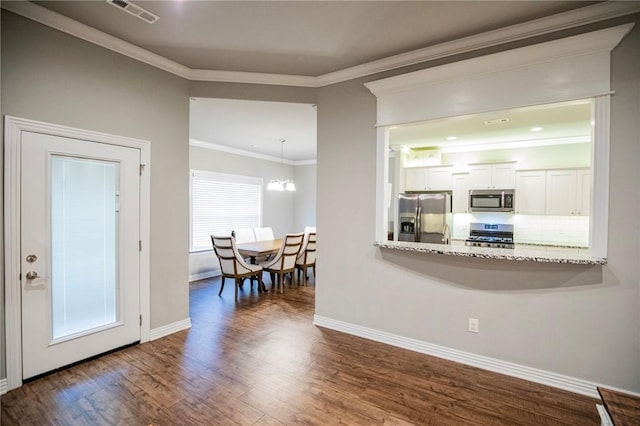 interior space featuring visible vents, baseboards, a notable chandelier, ornamental molding, and dark wood finished floors