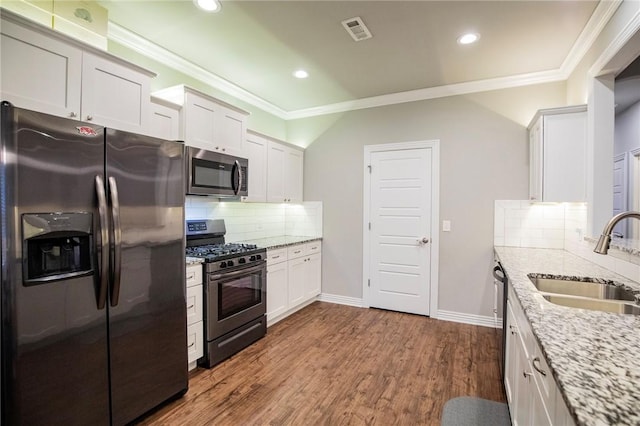 kitchen with a sink, visible vents, ornamental molding, and stainless steel appliances