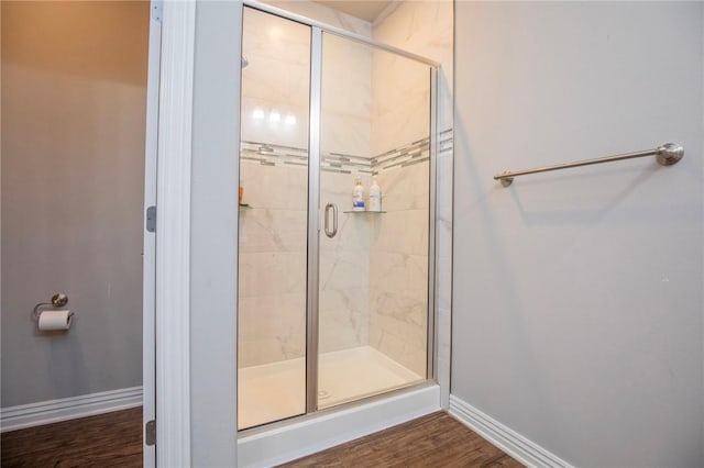 bathroom with baseboards, a stall shower, and wood finished floors