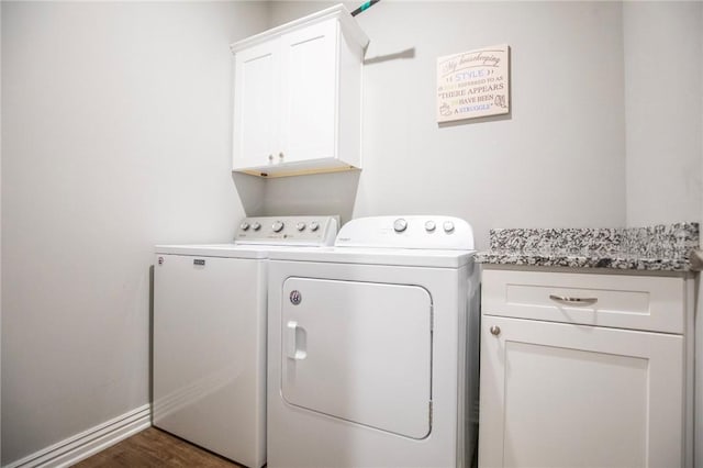 washroom featuring dark wood-type flooring, baseboards, washing machine and clothes dryer, and cabinet space