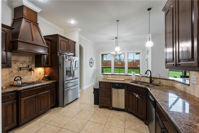 kitchen featuring custom range hood, a notable chandelier, dark brown cabinets, appliances with stainless steel finishes, and a sink