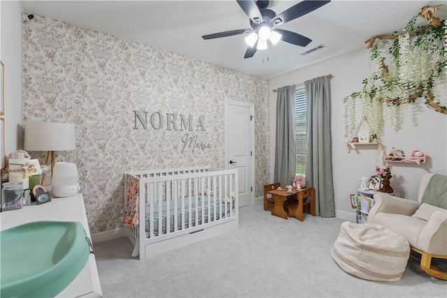 bedroom featuring wallpapered walls, a crib, visible vents, carpet, and a sink