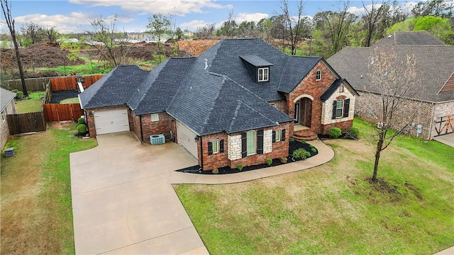 view of front facade featuring an attached garage, driveway, a front yard, and stone siding