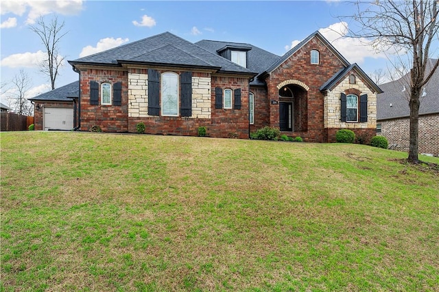 french country style house with a shingled roof, a garage, a front lawn, and brick siding