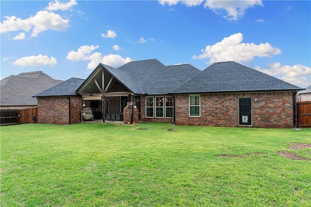 rear view of property with a shingled roof, brick siding, a fenced backyard, and a lawn