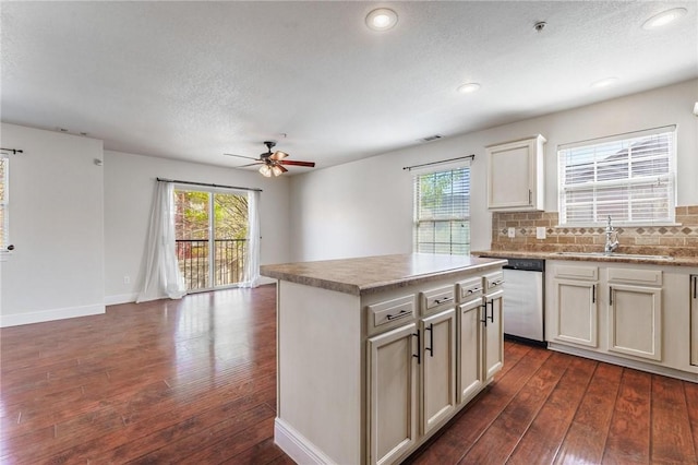 kitchen with a sink, stainless steel dishwasher, a ceiling fan, and dark wood-type flooring