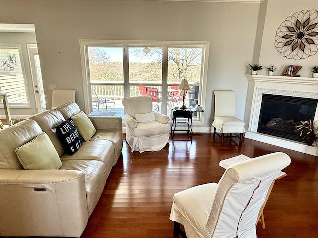 living area with baseboards, a tile fireplace, and wood finished floors