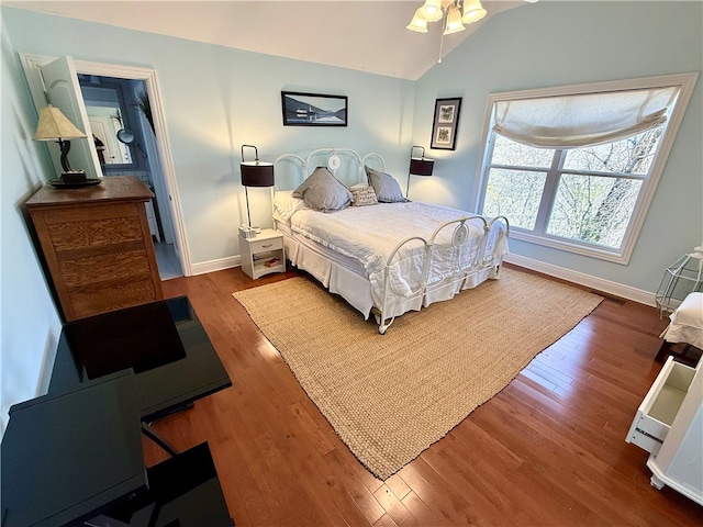 bedroom with vaulted ceiling, baseboards, and wood finished floors