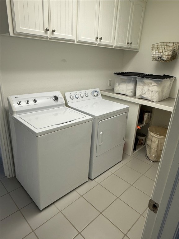 laundry area featuring washing machine and clothes dryer, light tile patterned floors, and cabinet space