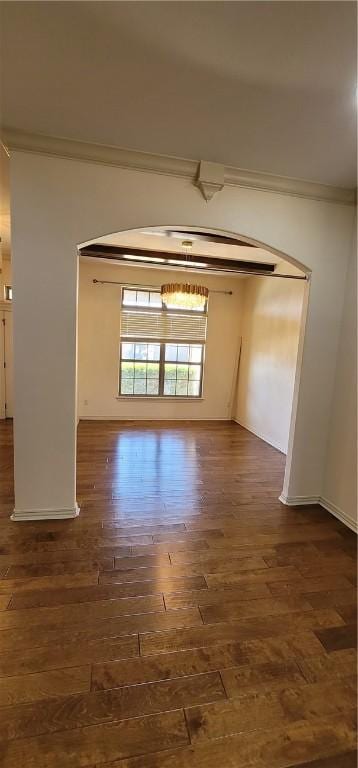 empty room featuring baseboards, crown molding, and wood finished floors
