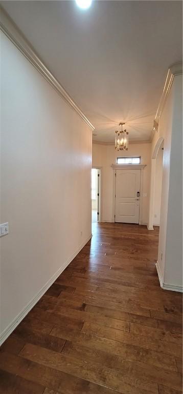 hallway featuring crown molding, an inviting chandelier, hardwood / wood-style floors, and arched walkways