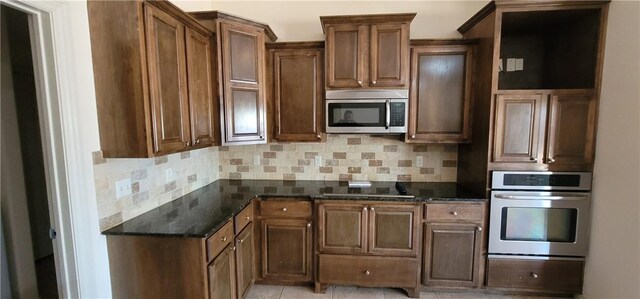 kitchen with stainless steel appliances, tasteful backsplash, and dark stone countertops