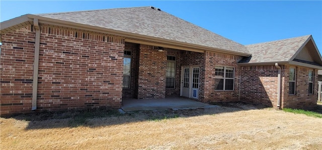 back of property with a patio area, brick siding, a yard, and a shingled roof