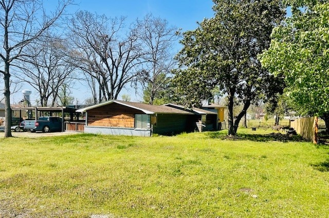 view of side of property featuring a yard, fence, and a carport