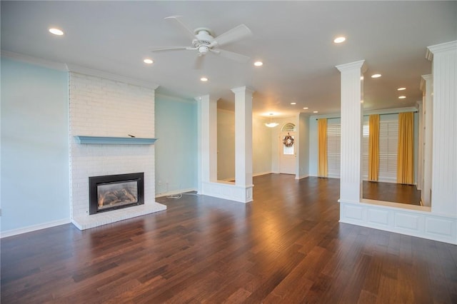 unfurnished living room with a brick fireplace, ornate columns, ornamental molding, and ceiling fan