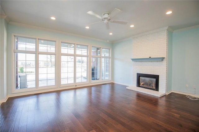 unfurnished living room with ornamental molding, recessed lighting, dark wood-type flooring, a brick fireplace, and ceiling fan