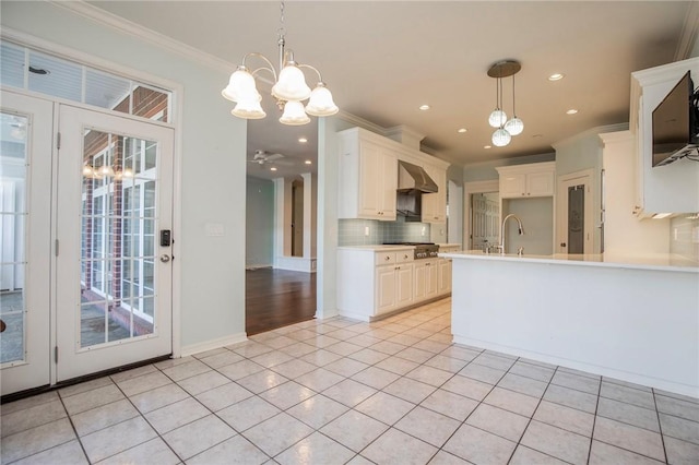 kitchen featuring stainless steel gas cooktop, decorative backsplash, wall chimney range hood, and ornamental molding