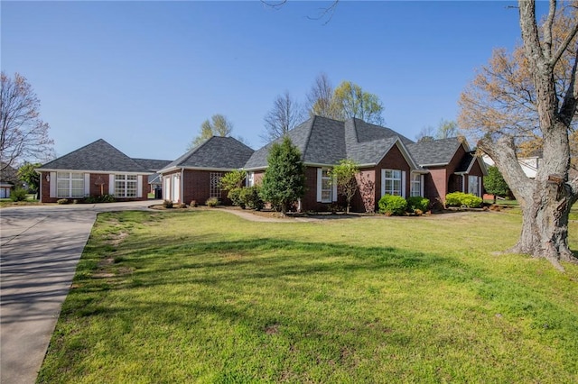 view of front of home with an attached garage, driveway, a front lawn, and brick siding