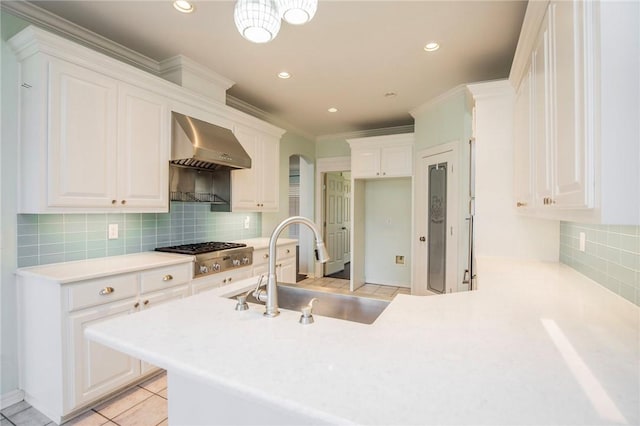 kitchen featuring a sink, wall chimney exhaust hood, white cabinetry, and stainless steel gas stovetop