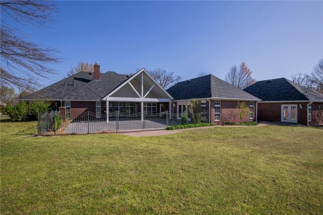 rear view of property featuring a yard, a chimney, a patio, brick siding, and french doors