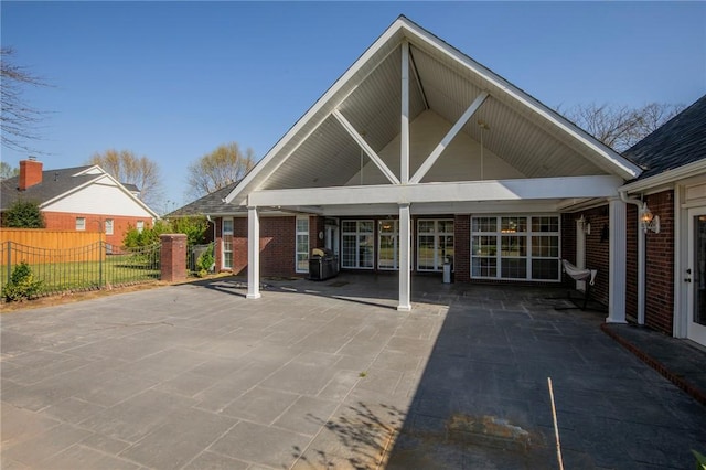 back of property with a patio area, fence, and brick siding