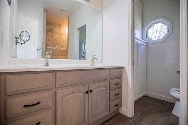 full bath with toilet, double vanity, and a sink