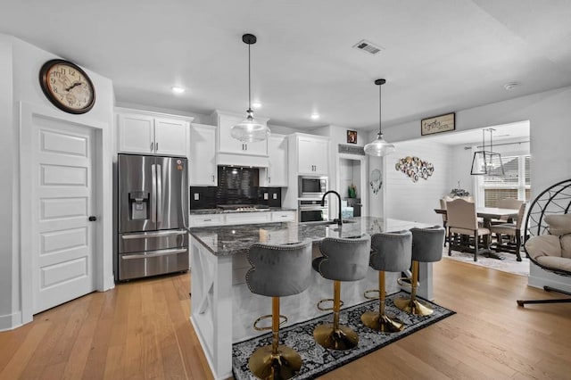 1241 Silver Maple St, Centerton, AR 72719 - kitchen with stainless steel appliances, a kitchen breakfast bar, white cabinets, light wood-style floors, and recessed lighting