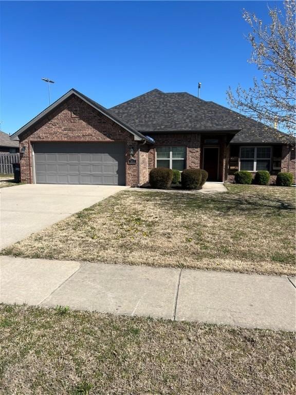 ranch-style house with an attached garage, concrete driveway, a front yard, and brick siding