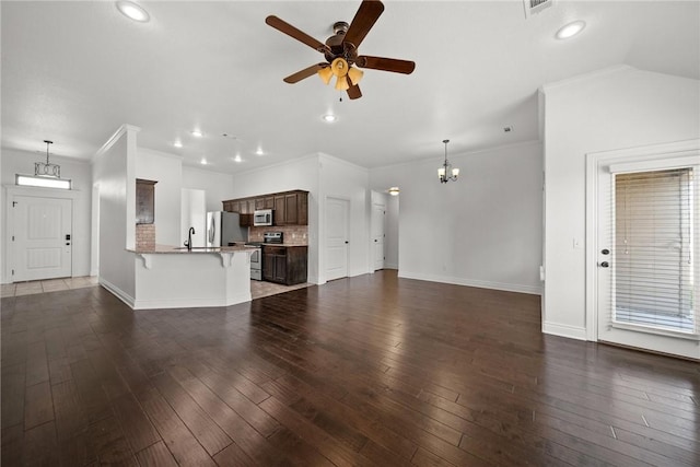 unfurnished living room featuring recessed lighting, baseboards, a sink, and ceiling fan with notable chandelier