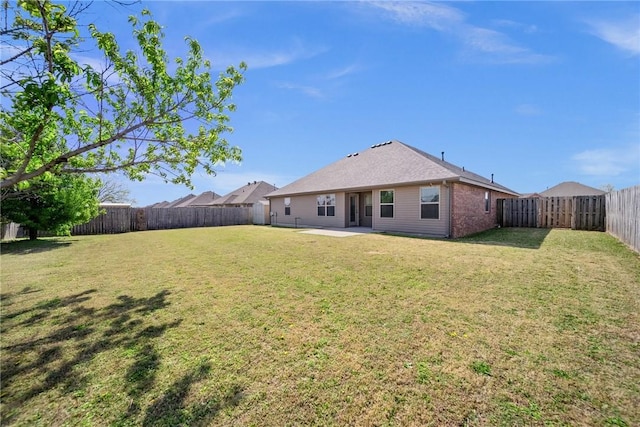 rear view of house with brick siding, a yard, a fenced backyard, and a patio