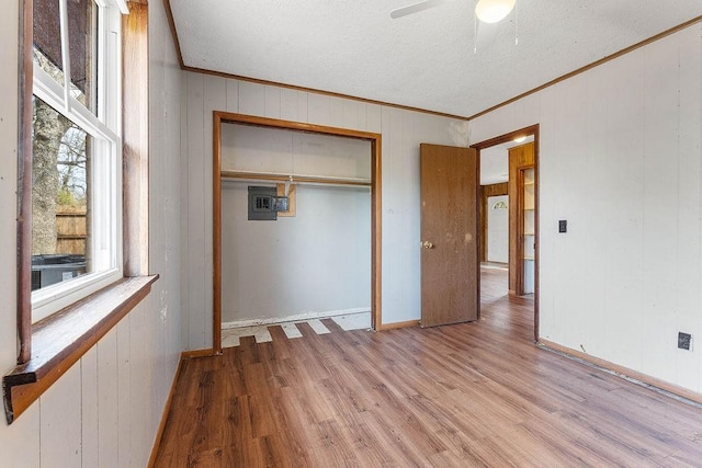 unfurnished bedroom featuring wood finished floors, wooden walls, a closet, and ornamental molding