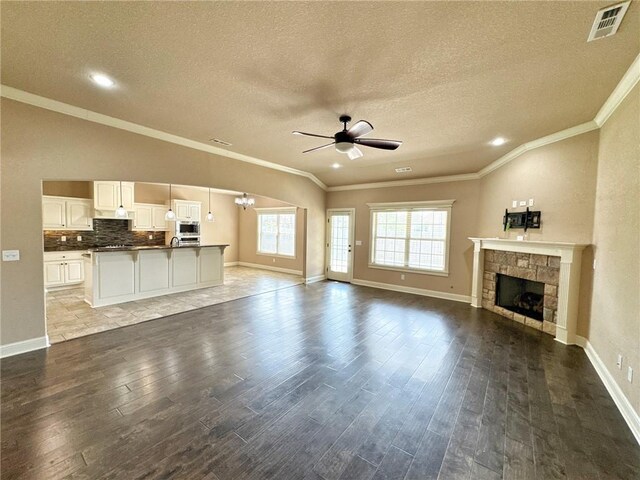 unfurnished living room with a ceiling fan, wood finished floors, a textured ceiling, and a stone fireplace